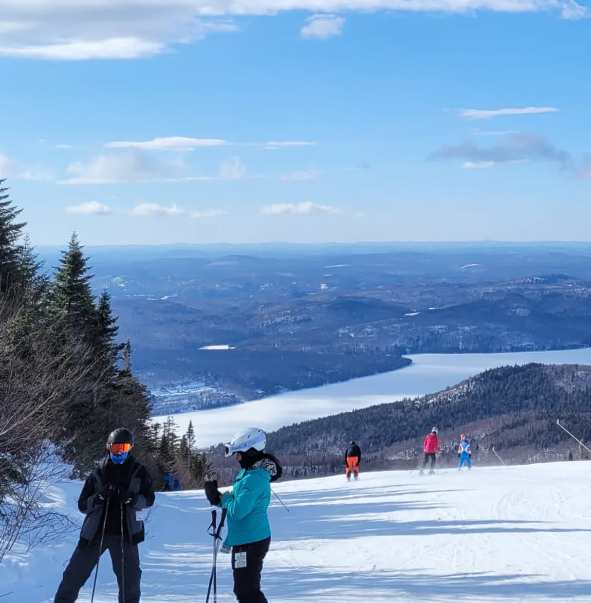 A croped frame of a winter mountain range with Lukas in forground in ski gear.